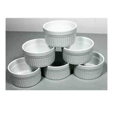 Stack of six white ceramic ramekins with ribbed sides on a gray surface