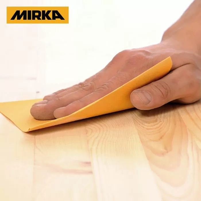 Hand sanding wood surface with yellow sandpaper sheet, Mirka logo visible, woodworking tool