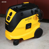 Yellow and black portable shop dust extractor vacuum on a workshop floor