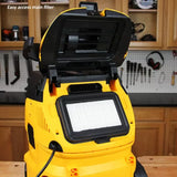Yellow shop vacuum with open lid showing main HEPA filter in a woodworking workshop