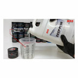 Pouring MAS Deep Pour epoxy resin into a mixing cup, with resin containers in background.