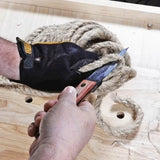 Person cutting thick sisal rope with a woodworking knife on a workbench