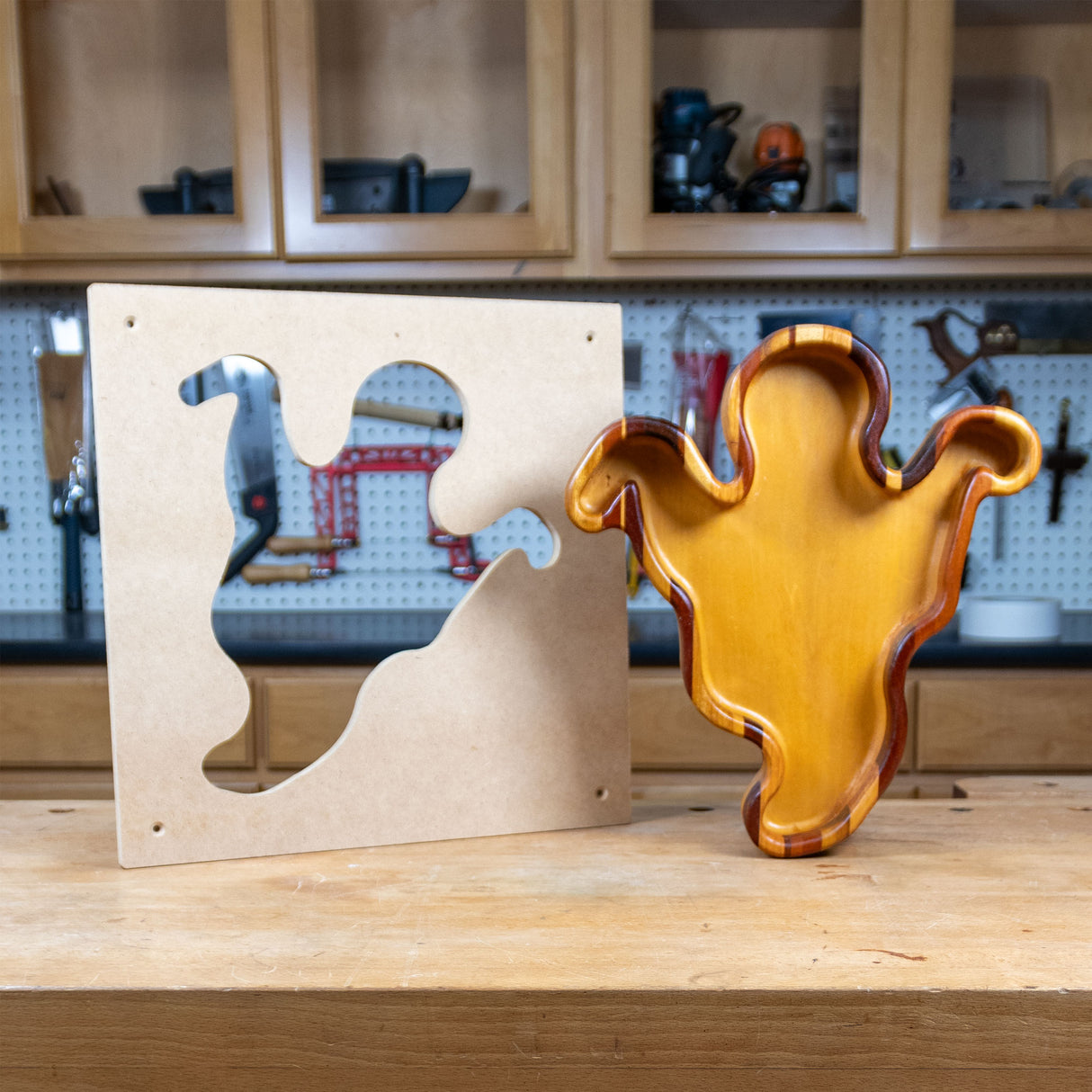 Ghost-shaped woodworking tray and MDF template on workshop bench, wood crafts template.