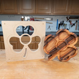 Shamrock-shaped woodworking template and finished wood tray on workbench in a workshop.