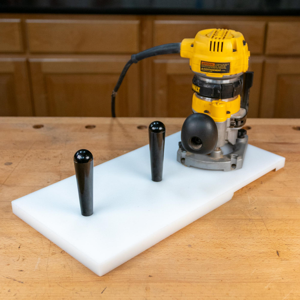 Woodworking router with custom router table sled and black handles on a workbench
