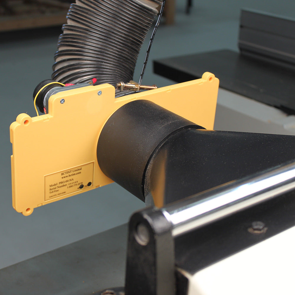 Woodworking dust collection hood with yellow safety guard attached to a machine table