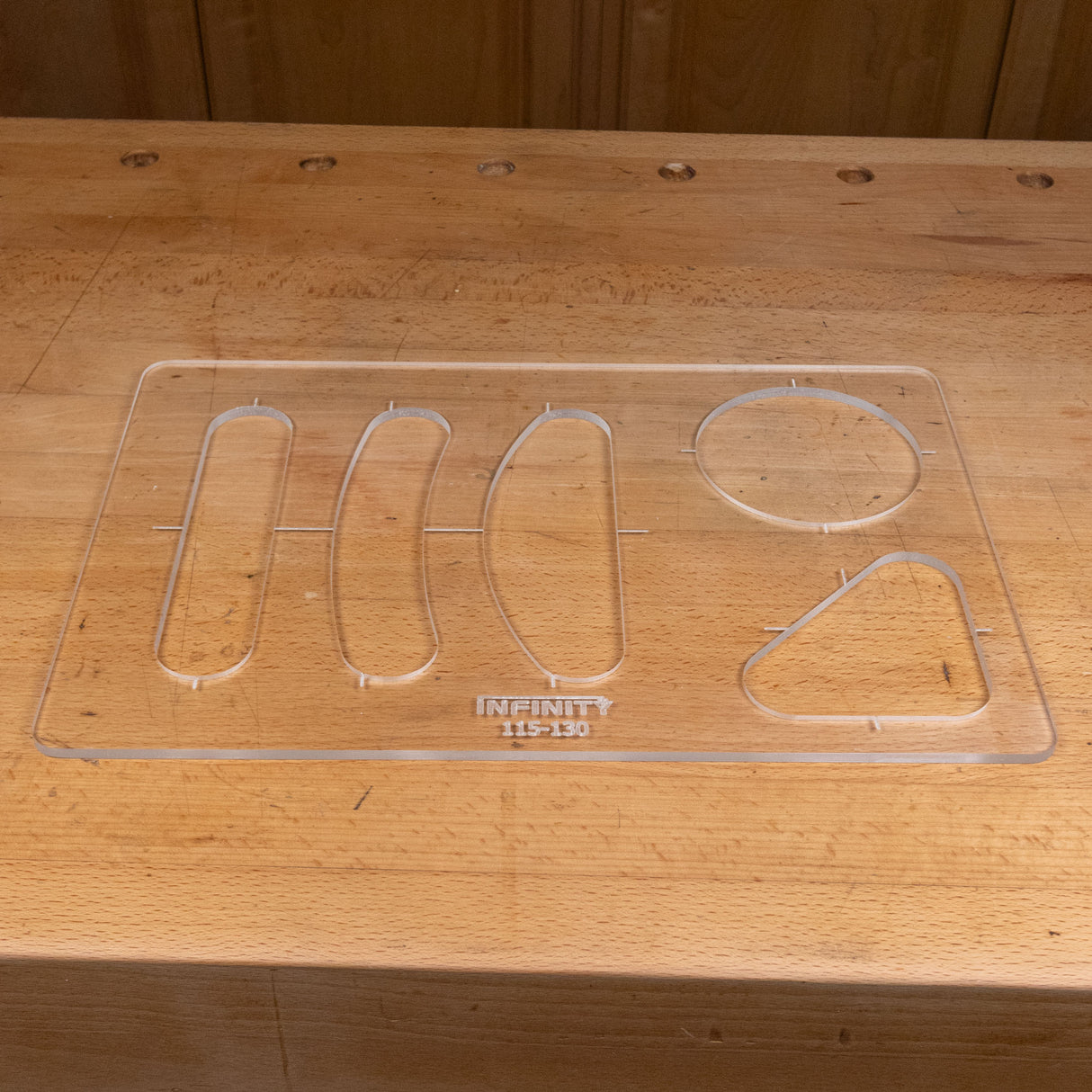Clear acrylic handle template with various shapes for woodworking on a wooden workbench