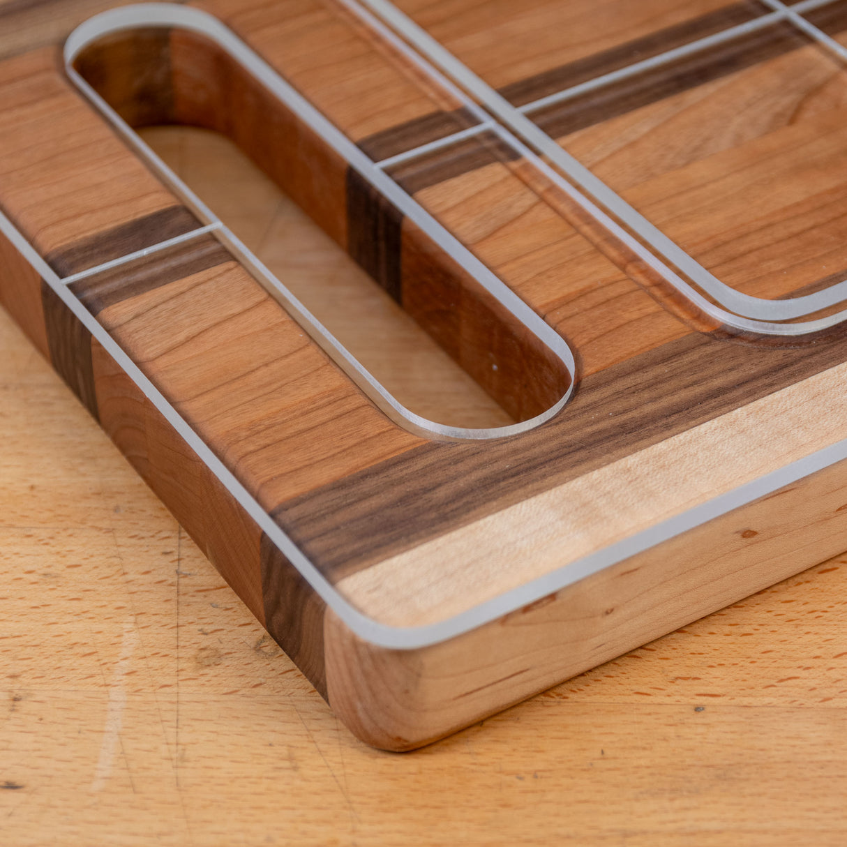 Closeup of acrylic cutting board template with rounded edges on a wooden surface