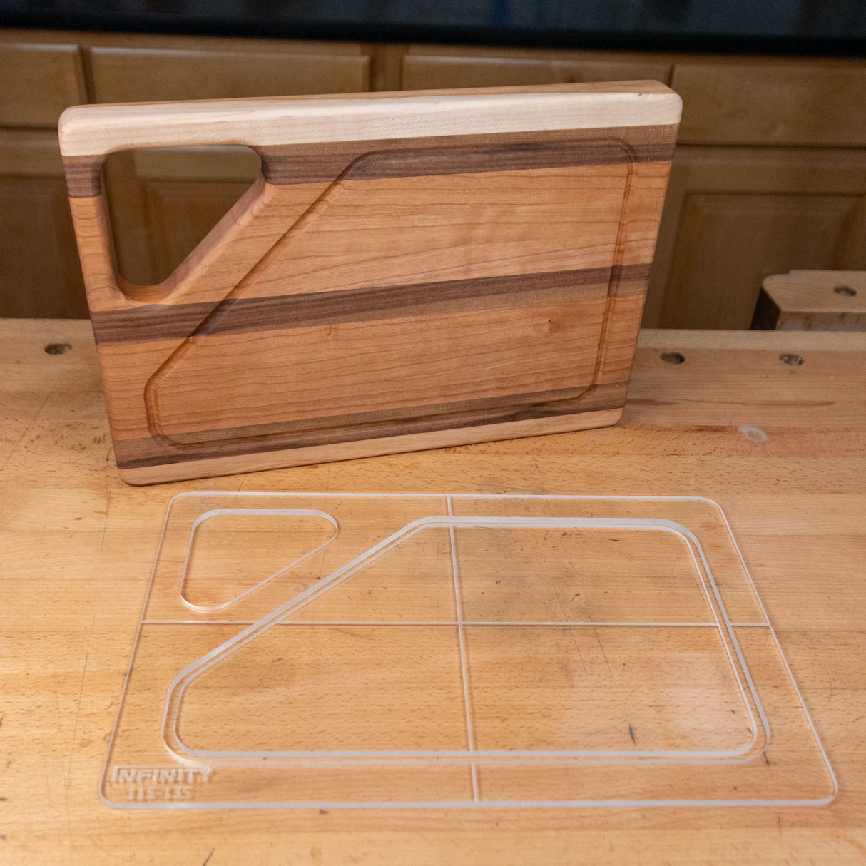 Clear acrylic cutting board template on workbench beside finished wooden cutting board