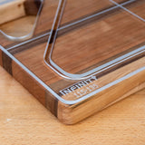 Acrylic cutting board template edge closeup on a wood surface, showing engraved markings.