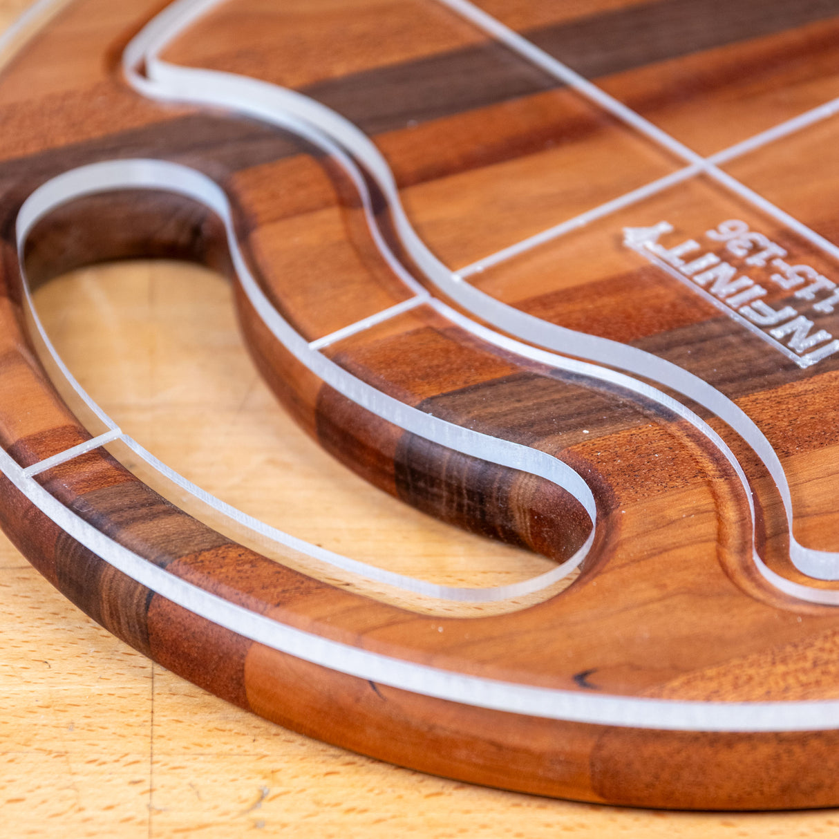Acrylic cutting board template closeup on wood surface, showing precision cut lines and handle shape