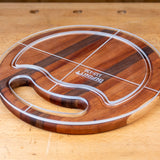 Acrylic cutting board template overlay on round wood cutting board with handle on workbench