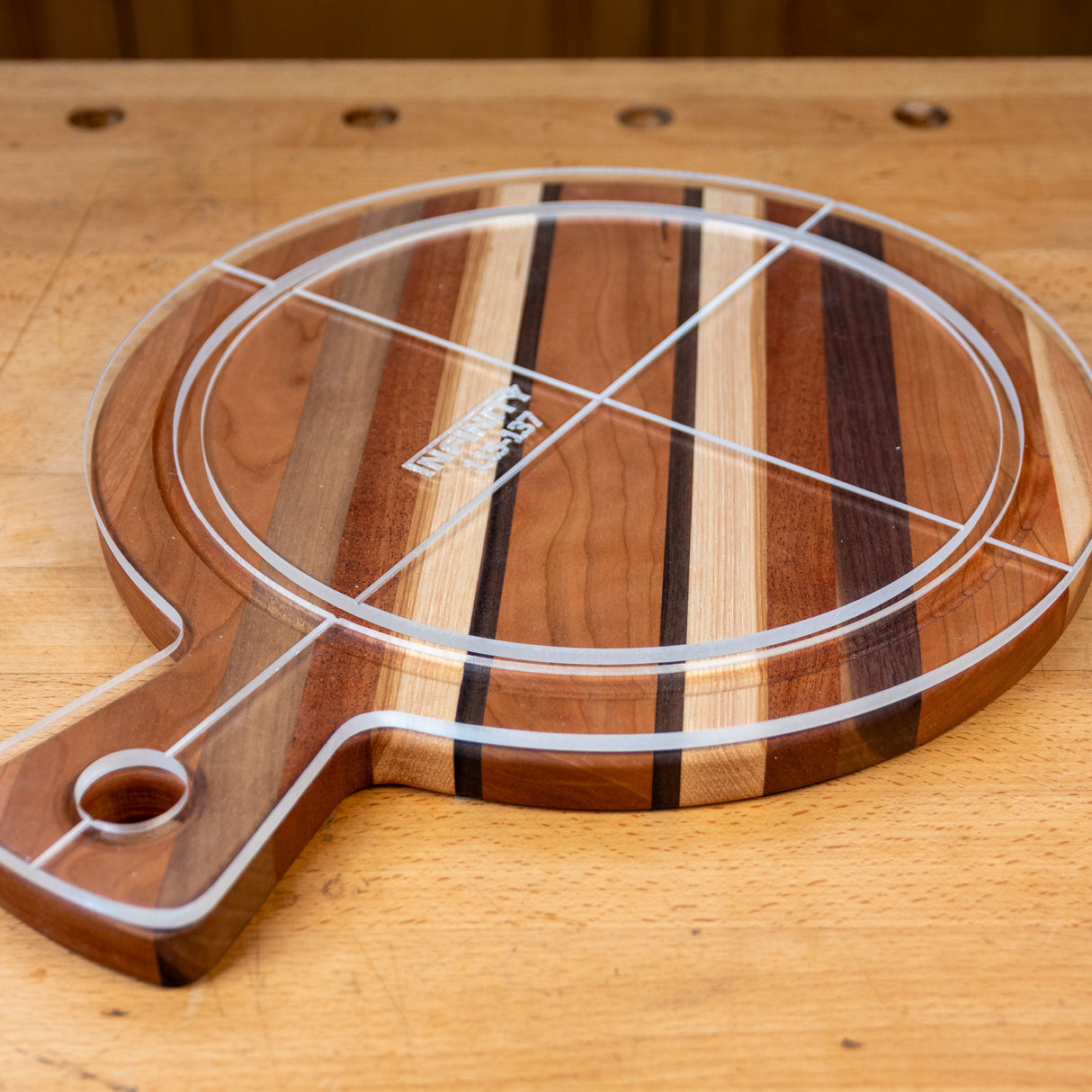 Acrylic cutting board template overlay on a round striped wood cutting board with handle
