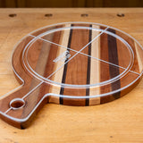 Acrylic cutting board template overlay on a round striped wood cutting board with handle