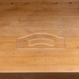 Clear acrylic handle template for woodworking placed on a wooden workbench.