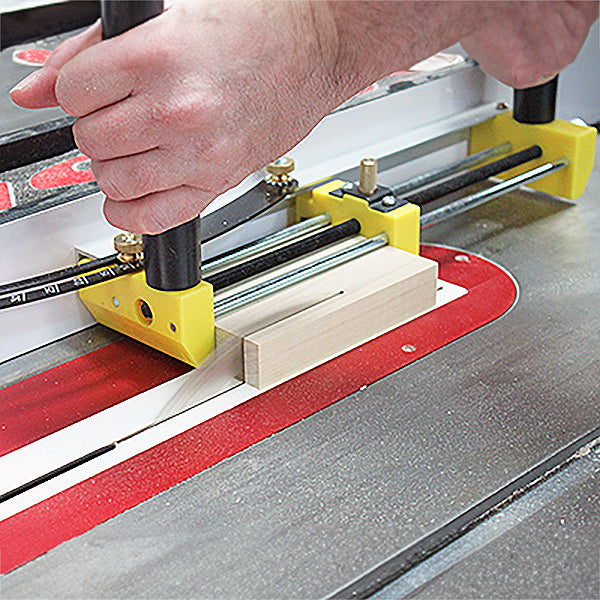 Woodworker using router table with precision fence and hold-down on a wood block