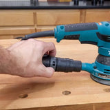 Hand connecting dust collection hose to orbital sander on woodworking bench