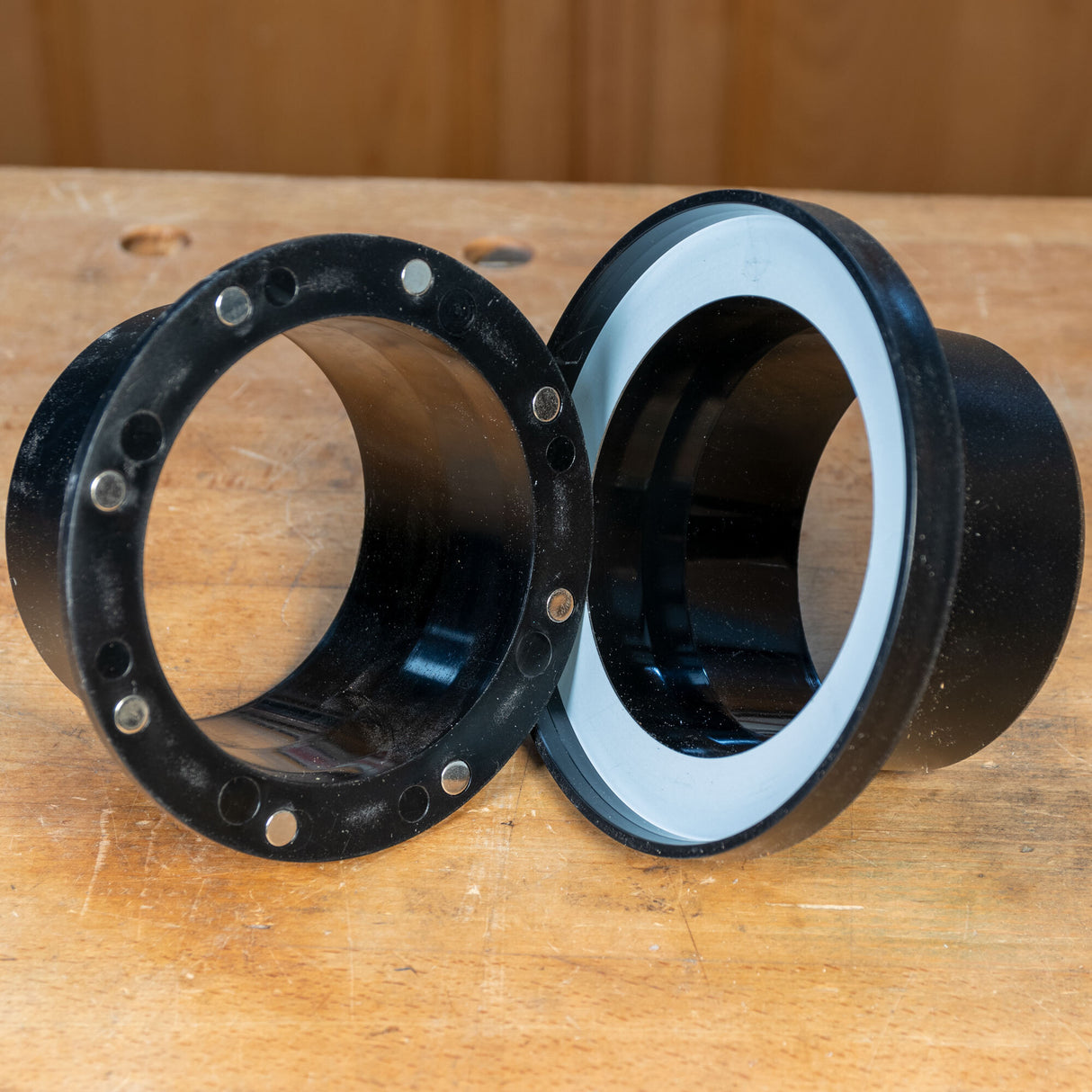 Black magnetic router table rings with embedded magnets on a wooden workbench
