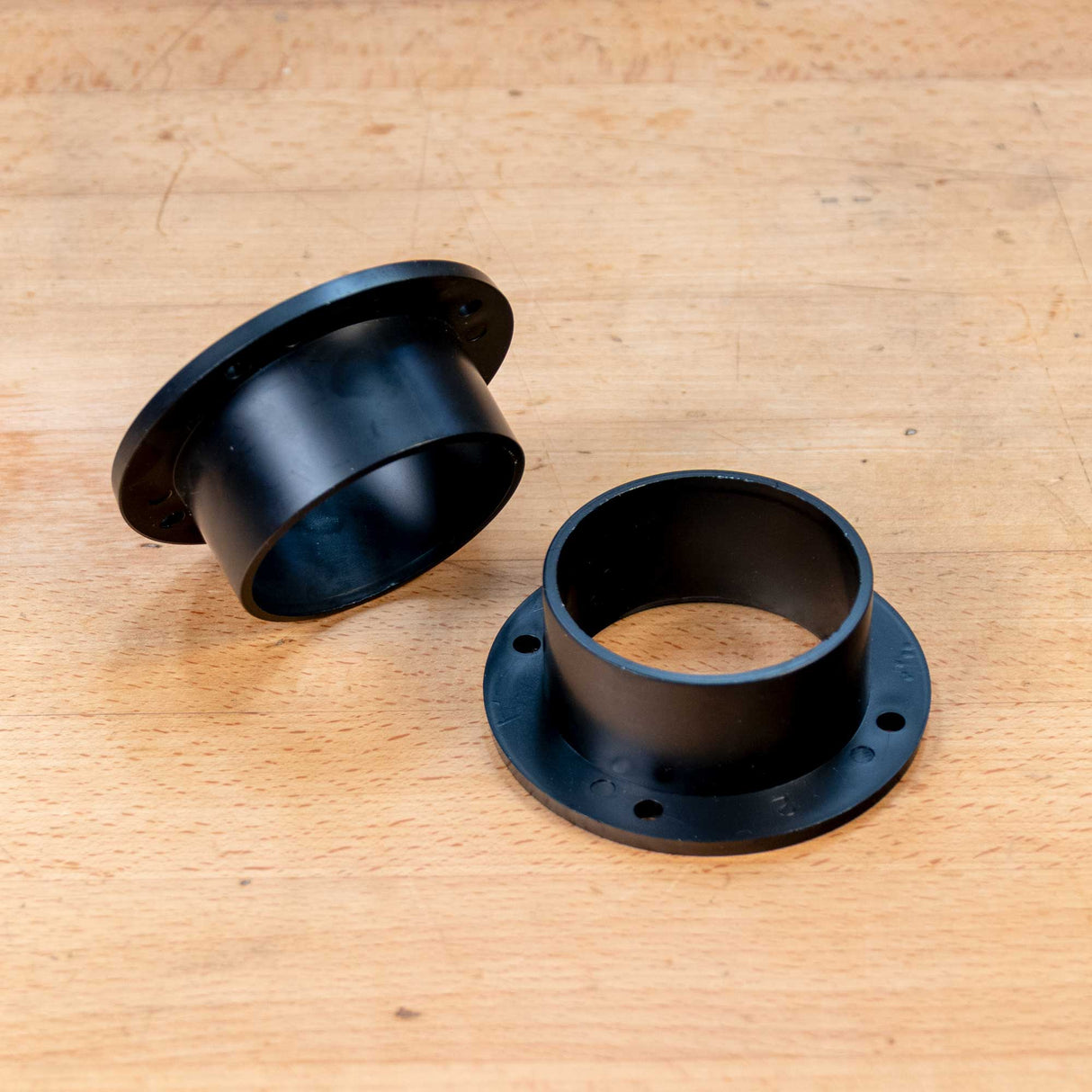 Two black 2-1/2 inch dust collection connectors on a wooden workbench