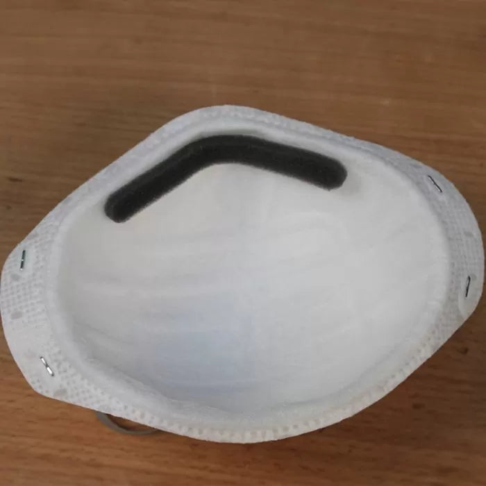 White dust mask with foam nose pad on a wood surface, woodworking safety gear