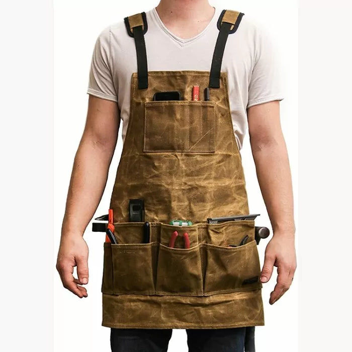 Man wearing a brown canvas woodworking apron with multiple pockets holding hand tools