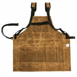 Brown waxed canvas woodworking apron with adjustable straps and front pockets, laid flat.