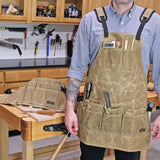 Woodworker wearing waxed canvas tool apron with pockets in a workshop setting.