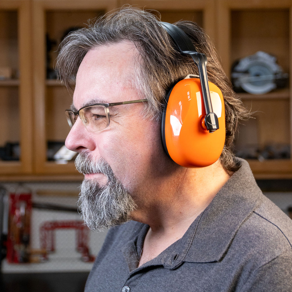 Man wearing orange NRR 24 earmuffs for hearing protection in woodworking shop