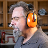 Man wearing orange NRR 24 earmuffs for hearing protection in woodworking shop