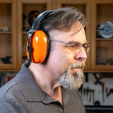 Man wearing orange noise reduction earmuffs in a woodworking shop setting