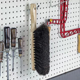 Wood handle bench brush hanging on pegboard with screwdrivers and woodworking tools