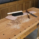 Woodworking bench with chisel, joinery, wood shavings, and cleaning brush