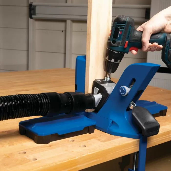 Pocket hole jig with dust collection attached, clamp and drill in use on workbench