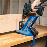 Pocket hole jig clamped to wood board with drill driver in woodworking workshop