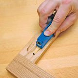 Hand using a blue pocket hole jig to align dowel joint in wood on a workbench.