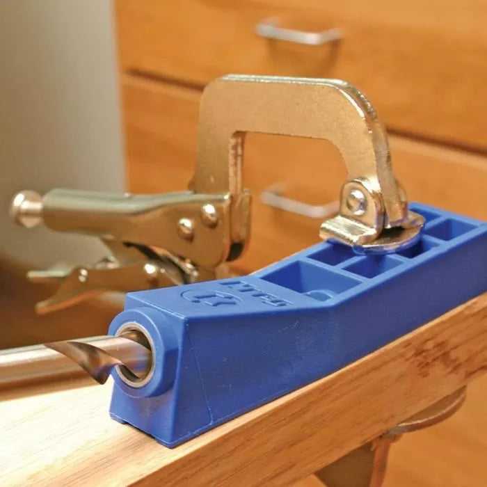 Pocket hole jig with drill bit and clamp secured to wooden board for woodworking