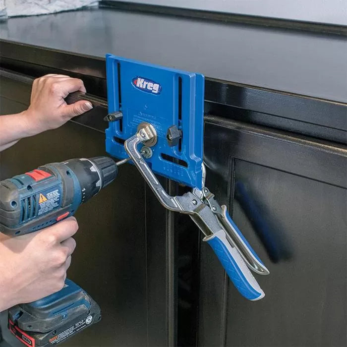 Person using a drill and a blue pocket hole jig clamped to a cabinet door