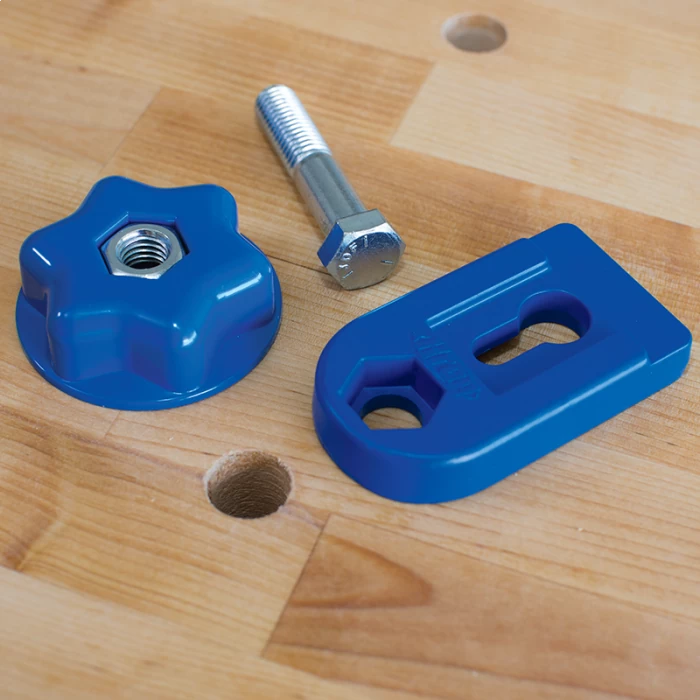 Workbench hold-down clamp kit with blue knob, clamp plate, and bolt on wood surface