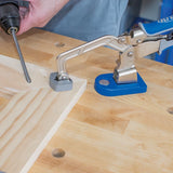 Pocket hole clamp securing wood joint on workbench with drill for woodworking assembly