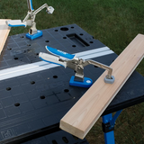 Woodworking table with metal toggle clamps holding wooden boards on a black work surface