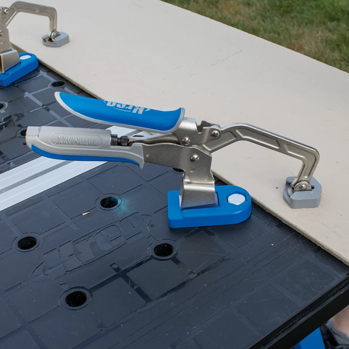 Kreg blue and silver woodworking clamp securing board on workbench outdoors