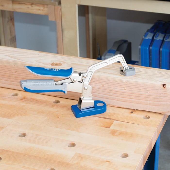 Woodworking clamp securing a wooden board on a workbench in a workshop setting