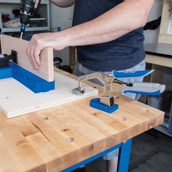 Woodworker using a drilling jig and toggle clamp to join boards on a workbench