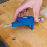 Hand adjusting blue woodworking jig tool on wooden workbench
