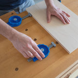Securing wood board with blue bench dog clamps on a woodworking workbench