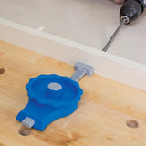 Blue woodworking jig clamped to a workbench, guiding a drill for precise hole placement