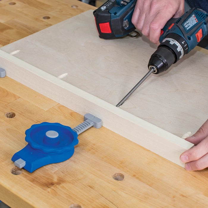 Person using power drill and woodworking clamp to assemble boards on a workbench