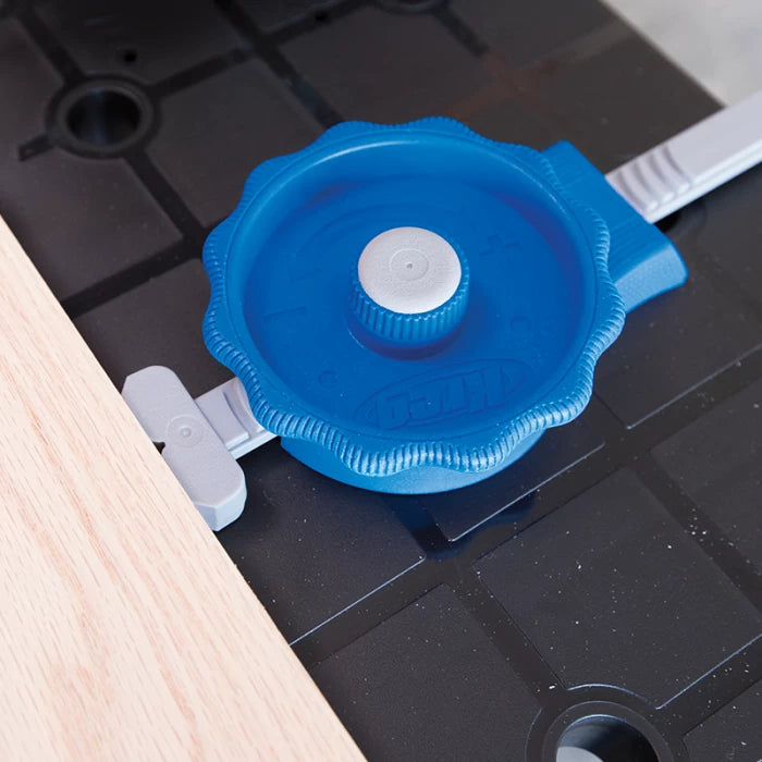 Blue adjustable woodworking clamp securing wood on a black workbench