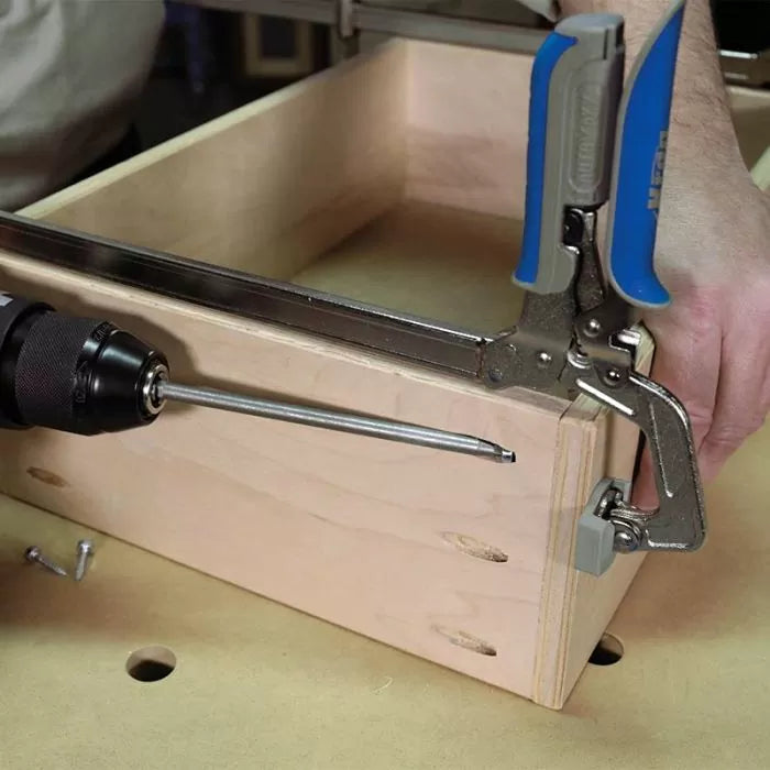 Woodworking pocket hole assembly with clamp and drill on a wooden drawer