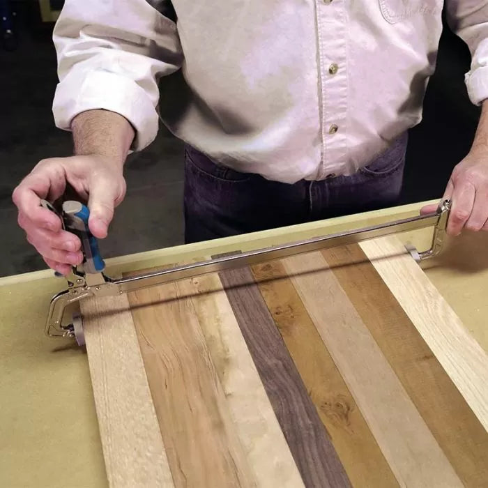 Woodworker using a frame clamp on a striped wooden panel for precise woodworking